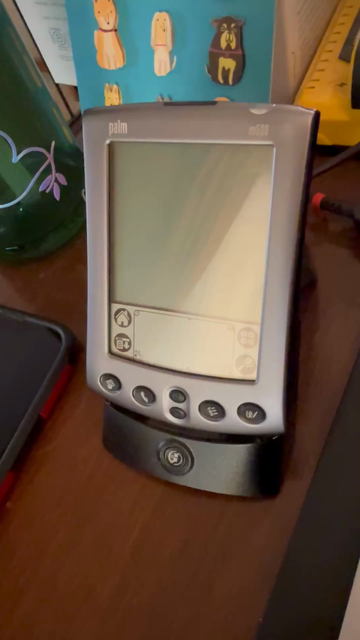 A Palm m500 PDA in its dock. The HotSync button on the dock is pressed and it makes the ascending 3 tone “hotsync starting” sound, synchronizes all the databases, then makes the same tone but descending to indicate it’s done. A Dalmatian whines at the end, out of sight